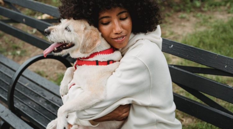 Lady hugging a dog whilst exercising outdoors