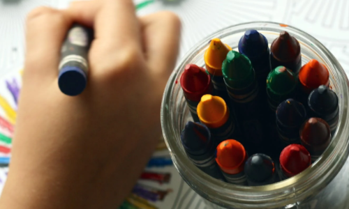 Child colouring with crayons