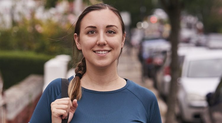 woman with yoga mat walking down city street