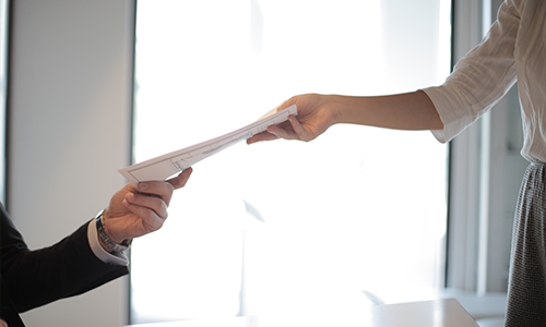 Woman handing man papers at work