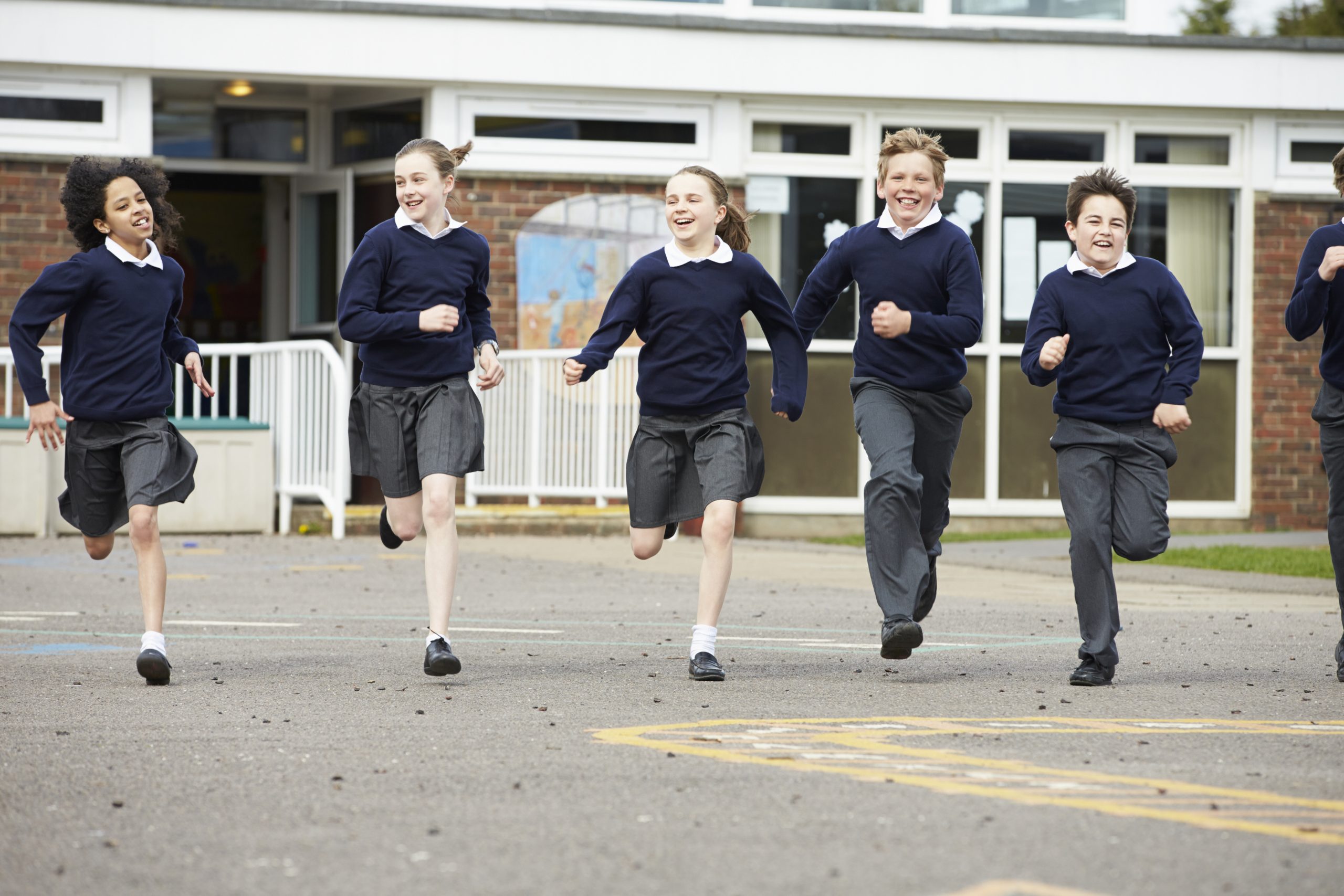 Group Of Elementary School Pupils Running In Playground