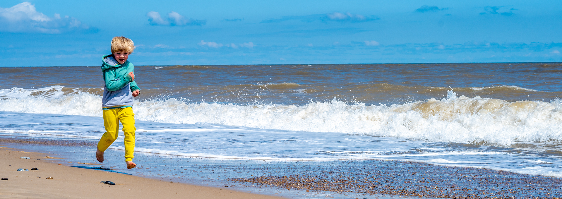 Boy running along a Norfolk beach