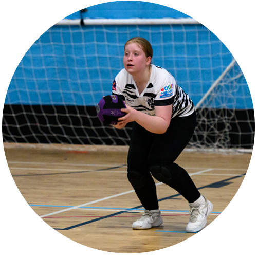 teenage girl playing dodgeball in a school